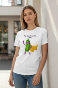 White cotton t-shirt with a cartoon superhero pickle and purple text that says "My dad, He's a big Dill!" by Here's the T's LLC.